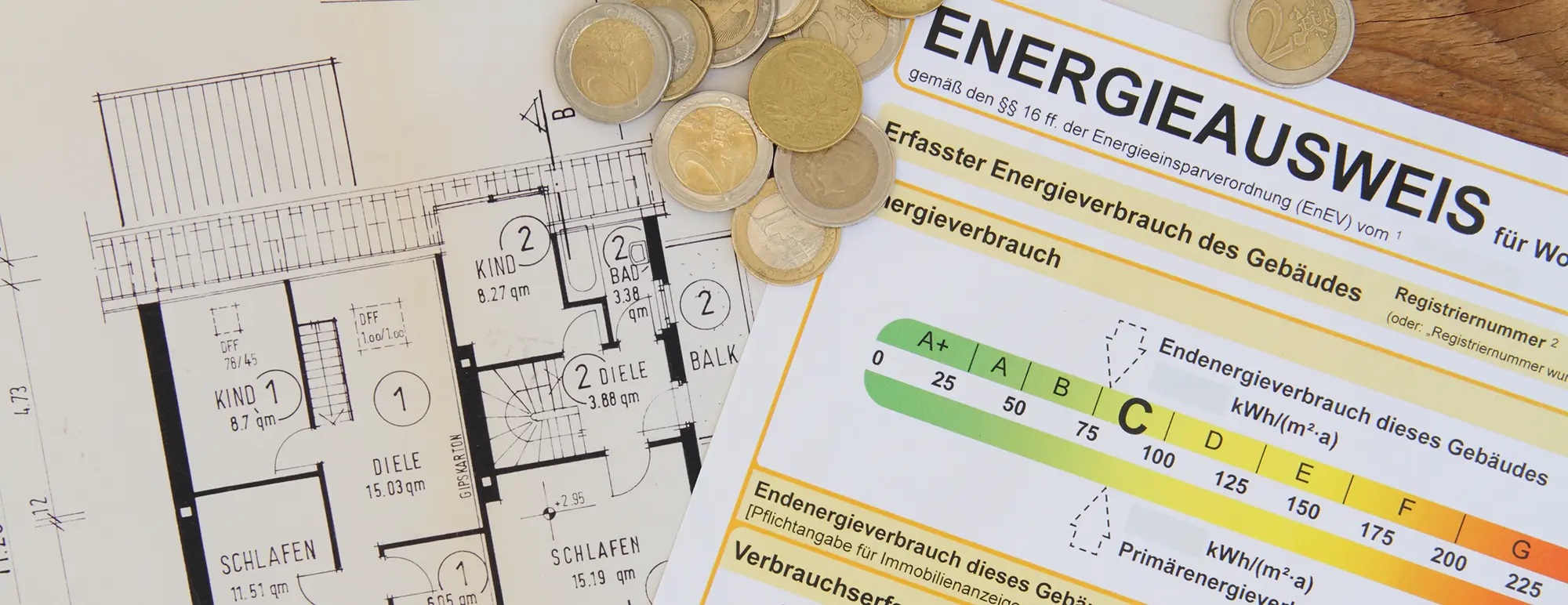 Energieausweis und Gebäudeplan mit darauf liegenden Geldmünzen